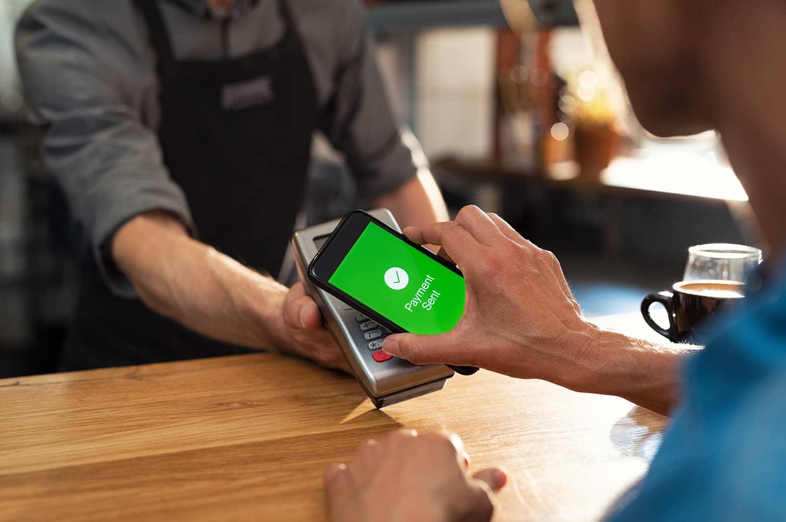 Customer paying bill through smartphone using NFC technology. Closeup of hand making payment through contactless machine. Woman hand holding mobile phone with green screen and paying the bill with contact less technology.